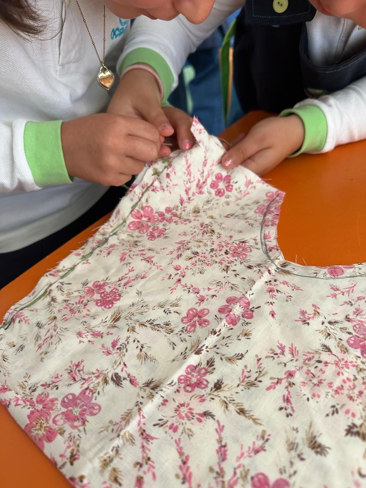 Duas crianças a trabalhar num vestido de tecido florido