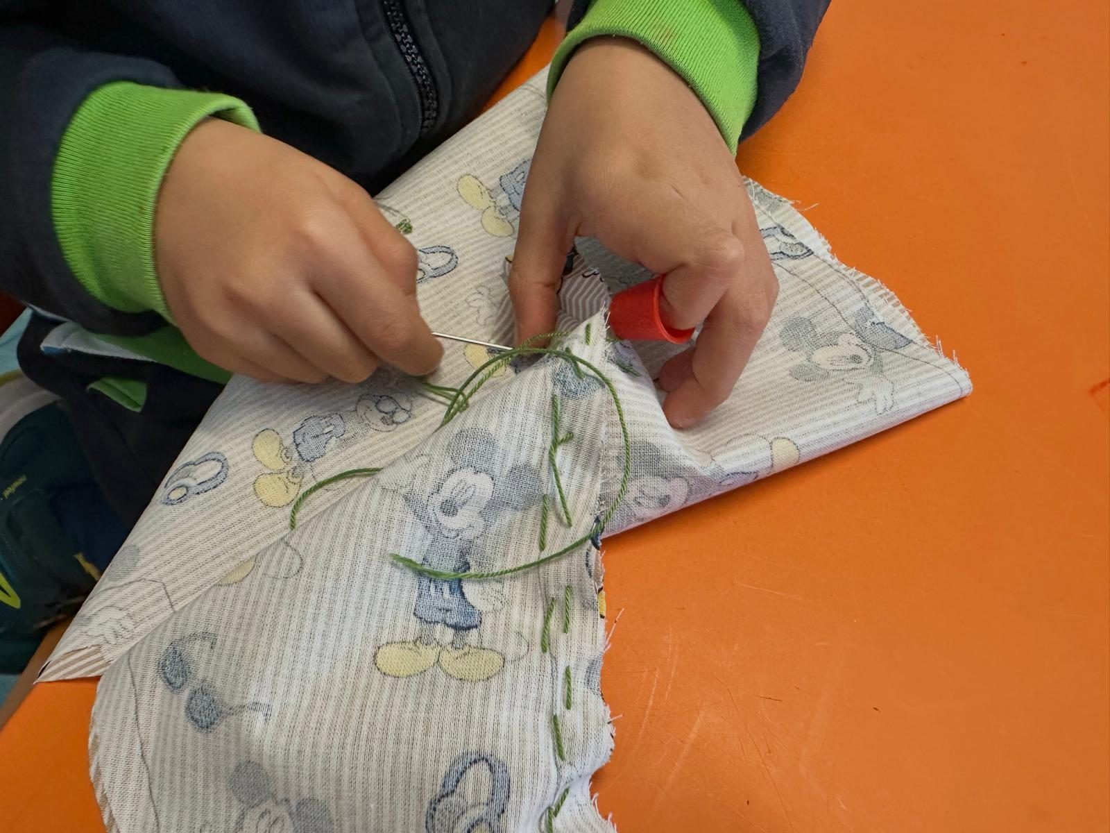 Criança a coser uma peça de roupa de bebé