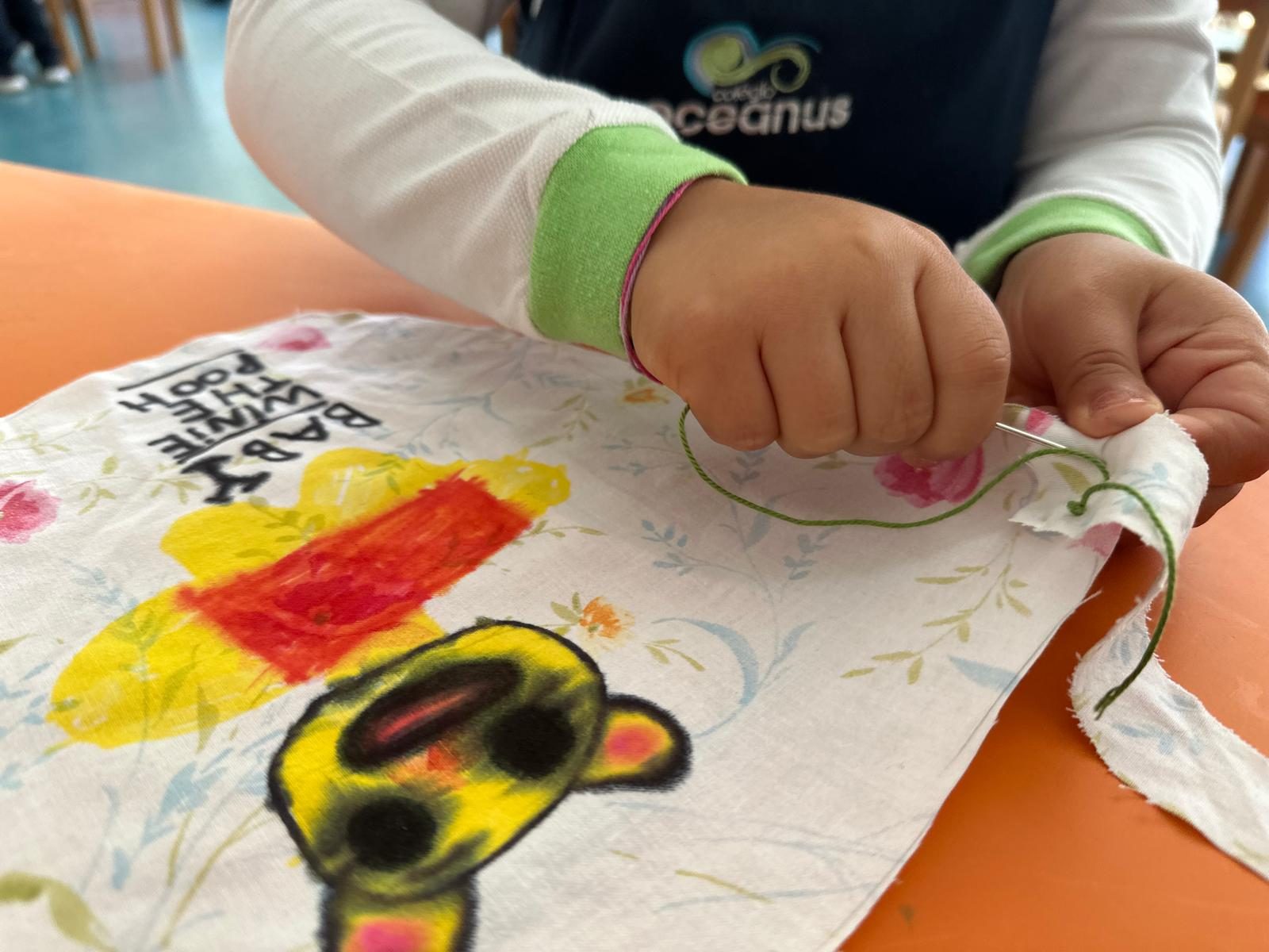 Criança a coser um tecido pintado
